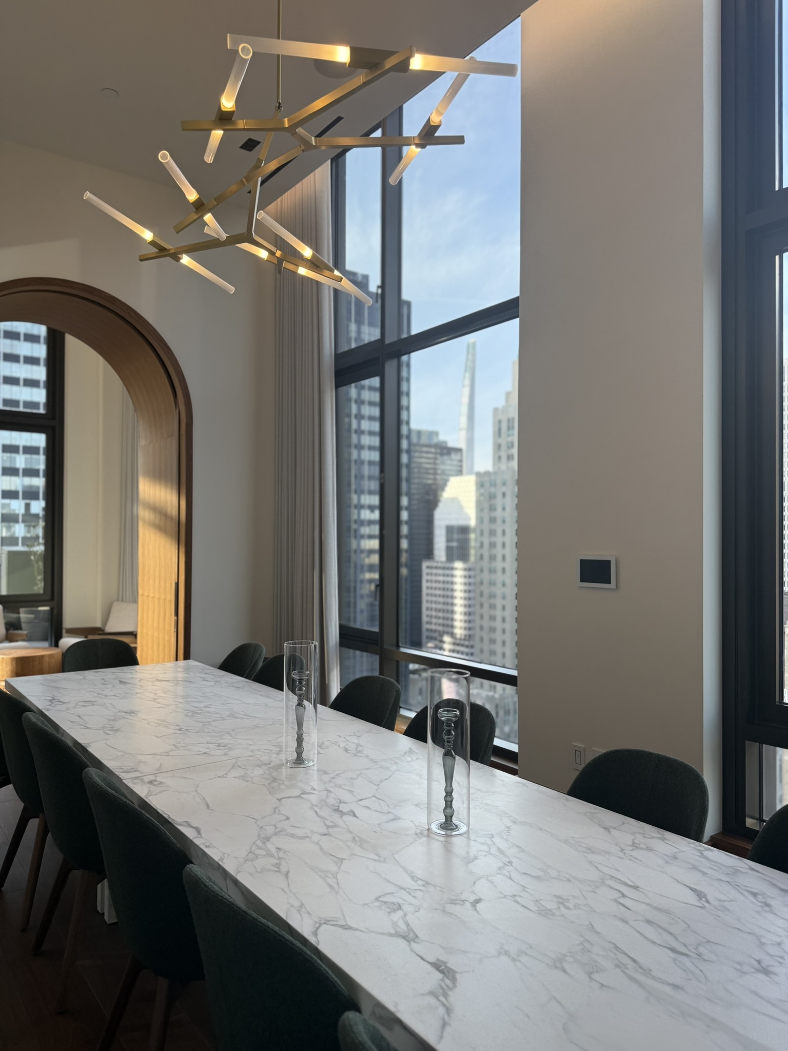 Sculptural chandelier, integrated shades, and warm woodwork in a Manhattan dining room